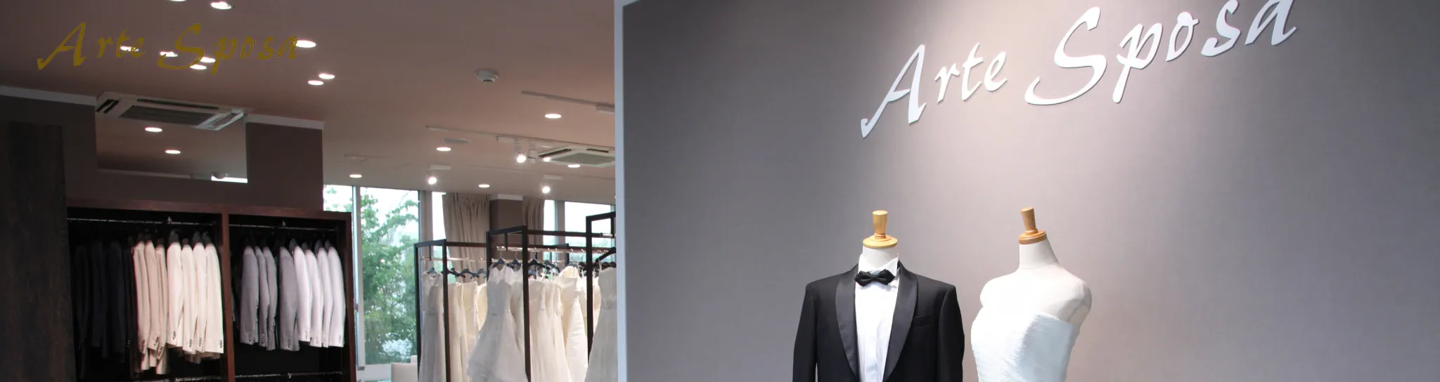 ブライダルショップ「Arte Sposa」の店内。左側にはタキシードとウェディングドレスが並び、右側にはタキシードとウェディングドレスを着たマネキンが展示されている