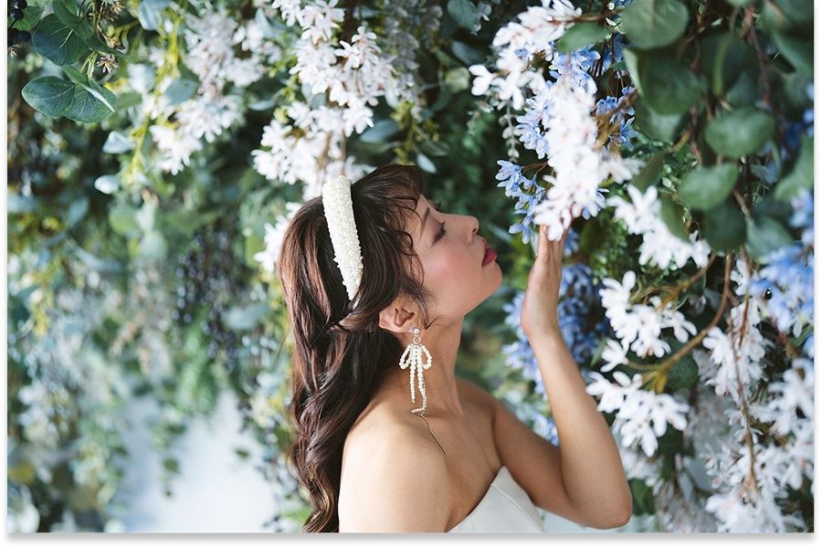 パールのヘッドドレスと白いドレス姿の花嫁が小花に囲まれた横顔
  